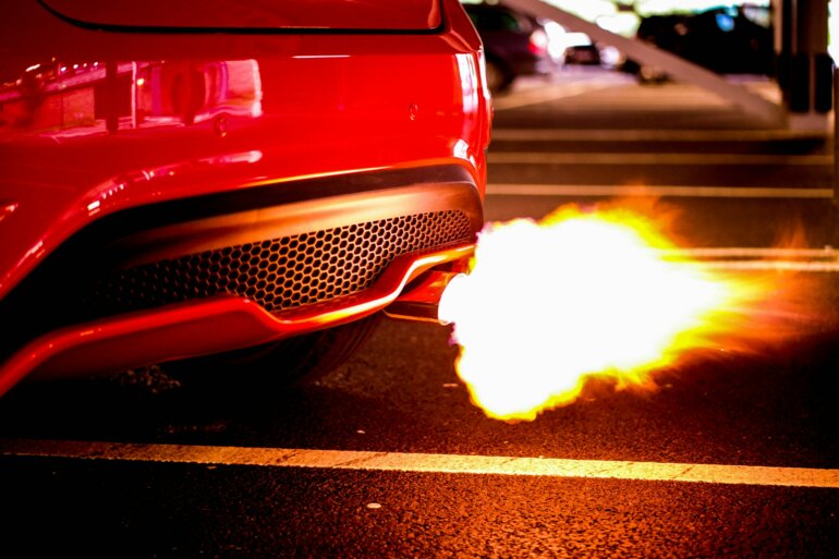 Symbolbild: Feuer aus einem Autoauspuff. Viele Fehlanreize sorgen für Energieverschwendung.